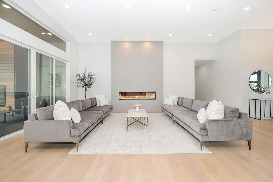 A bright open living room with two long grey sofas facing each other across a rug